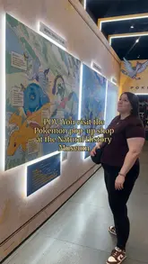 A short, handheld-style video tour of the Pokemon pop-up shop located within the Natural History Museum, showcasing the available merchandise, themed wall art, and a diorama display.