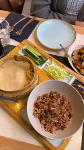 A video review of a Malaysian restaurant in Leeds, featuring the creator trying various dishes including duck pancakes, roti prata, char kuey teow, and kung po prawns, accompanied by an Asahi beer.