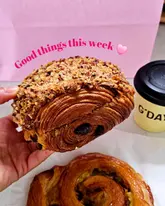 A casual, handheld shot of a pastry and coffee, likely taken for a 'day in the life' style post. The focus is on the food, but the photography is amateur.