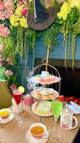 A visually appealing, polished montage showcasing a Wicked-themed afternoon tea experience at The Clermont London, featuring thematic decor, tea, sandwiches, scones, and cocktails.