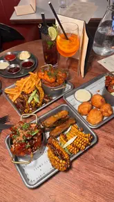 A short, fast-paced video promoting a bottomless wings and sides deal at Dirty Bones. The video features close-up shots of various wing flavors, sides like mac and cheese bites and corn, and cocktails, with text overlays detailing the offer price and terms.