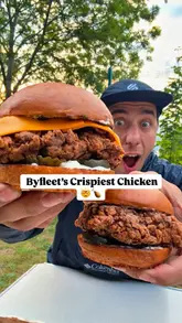 A high-energy food review of 'Clucking Crispy' in Byfleet, featuring a variety of fried chicken dishes including burgers, wings, sides like sweet potato fries and mac and cheese, and homemade cookies. The creator highlights the 'Michelin-trained' background of the chef and emphasizes the crispiness and flavor of the food.