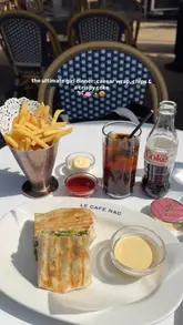 A short, aesthetic montage featuring a meal at Le Cafe Nac in Knightsbridge, consisting of a chicken caesar wrap, chips, a Diet Coke, and a cookie with soft-serve ice cream. The video uses slow-motion shots and text overlays to highlight the 'girl dinner' trend.