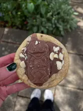 A close-up, handheld shot of a cookie topped with a Freddo chocolate bar, likely from a coffee shop.