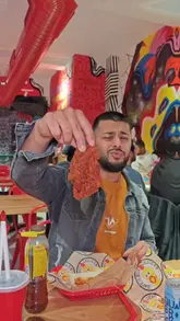 The video features a creator visiting Dave's Hot Chicken in Croydon for a community event. It provides a behind-the-scenes look at the kitchen's frying and seasoning process, showcases the menu items including sliders, tenders, and loaded fries, and captures the lively atmosphere of the event.