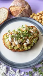 A step-by-step recipe tutorial for avocado toast topped with chickpeas, feta, and chilli oil, filmed from a top-down perspective.