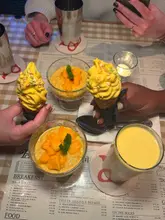 A top-down, flat-lay style shot of a table at Dishoom Permit Room, featuring mango-themed desserts and drinks served on a menu placemat.