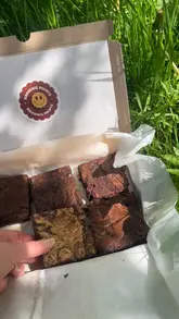 A short, handheld video showcasing a box of gluten-free brownies. The creator opens the box, displays the individual brownies, and breaks one open to reveal the texture.