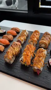 A montage of various Japanese-inspired dishes including sushi, gyoza, karaage, and loaded noodle bowls, filmed in a casual dining setting.