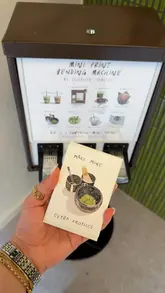 The video features a visit to Frothee cafe in Covent Garden, showcasing a unique 'mini print vending machine' pop-up by artist Eleanor Isobelle. The creator demonstrates how to use the machine to get a surprise art print and then enjoys a matcha latte.