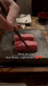 A couple enjoys an interactive dining experience at a restaurant, cooking fresh seafood and A5 Wagyu beef on a hot stone. The video captures the preparation, the cooking process, and the enjoyment of the meal, highlighting the unique and engaging nature of the venue.