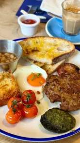 A short, punchy montage of breakfast dishes at a cafe, featuring close-up shots of a breakfast muffin being pressed, coffee, a full breakfast plate, and a Dutch pancake.
