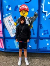 A promotional image featuring a child standing in front of a Legoland-themed wall, used to advertise a ticket deal for UK theme parks.