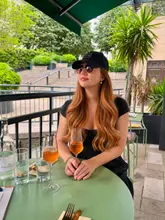 A portrait of a woman enjoying a drink at an outdoor table, capturing a relaxed summer vibe at a wine bar.
