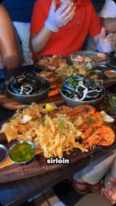 A creator reviews a seafood platter at Sea Garden & Grill, highlighting the variety of dishes including steak, squid, mussels, and prawns, paired with cocktails.