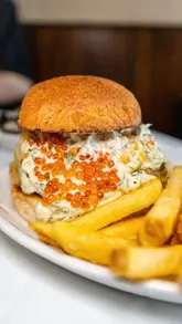 A high-quality montage of dishes at Belly Bistro, featuring a tempura cod burger, seafood caldereta, chargrilled scallops, and a dessert with a purple sauce. The video focuses on close-up, appetizing shots of the food presentation.