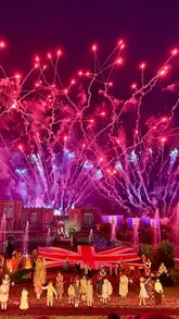A wide-angle, night-time shot of the Kynren live-action show, capturing a large Union Jack flag on stage, performers, and a dramatic fireworks display illuminating the sky.