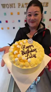 A creator visits Woni Patisserie in London to pick up a custom mango birthday cake, showcasing the shop's display and the cake's quality during a celebration.