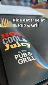 A montage of various dishes including burgers, bao buns, and desserts, interspersed with shots of children eating at a Village Hotel Pub & Grill, promoting a 'kids eat free' offer.