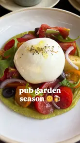 A short, fast-paced montage showcasing a variety of dishes from a pub's summer menu, including wings, a cheese soufflé, scallops, a tomato and burrata salad, and a basque cheesecake, set against the backdrop of the pub's garden and covered seating area.