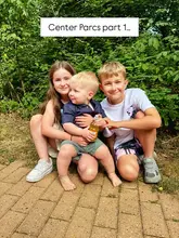 A candid, outdoor family photo taken at Center Parcs, featuring three children posing together in a wooded area. The image captures a family holiday moment, highlighting the outdoor, nature-focused environment of the resort.