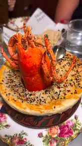 A review of Empire Empire, a 1970s-style Indian restaurant in London, showcasing various dishes including lamb chops, a tandoor grilled platter, butter chicken, lobster biryani, prawn masala, and desserts.