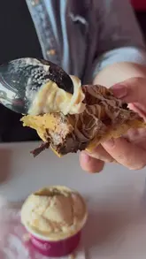 The creator visits 'Moonlight' in Liverpool, a dessert and junk food venue. The video features a variety of items including a brownie-stuffed waffle, a slush, a milkshake, a hot dog, a pizza, and cookie dough. The creator provides a review of the food, highlighting the indulgent nature of the menu and suggesting it as a great spot for after a night out.