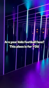 A visually striking, symmetrical shot of a neon-lit corridor at TOCA Social, an interactive football-themed activity venue. The lighting creates an immersive, futuristic atmosphere that effectively showcases the venue's unique design.