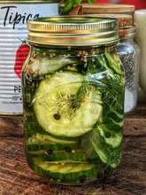 Homemade pickles in jars with cucumbers and spices, perfect for burgers or snacks, recipe shared by Team Pickles!