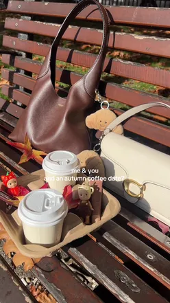 Two friends enjoying coffee and pastries in a sunny autumn setting in Leeds, surrounded by autumn leaves.