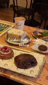 A short, aesthetic montage showcasing the interior and food offerings of Fred Bakery in London. The video features shots of the storefront, a table spread with pastries and a sandwich, merchandise, and a staff member preparing coffee.