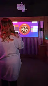 A creator visits Boom Battle Bar, highlighting the interactive darts experience, the variety of cocktails, and the food options available as part of a value deal. The video captures the fun atmosphere of the venue.
