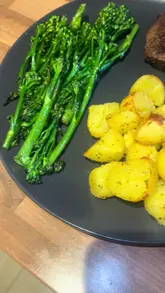 Grilled fillet steak, roasted baby potatoes, steamed broccoli, and creamy pepper sauce on a plate.