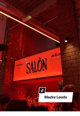 Vibrant red interior of Madre restaurant in Leeds, showcasing delicious tacos and refreshing margaritas on a table.