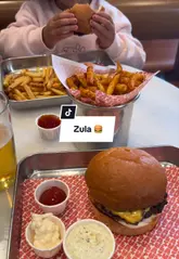 A short, informative review of Zula, a burger spot in London. The video features a voiceover describing the menu, specifically highlighting the unique 'Mi Goreng' burger, and provides shots of the interior, exterior, and the food served.