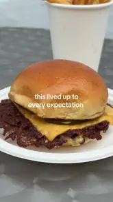 A short, punchy review video featuring a smash burger from Dumbo in Shoreditch, showcasing the cooking process, the final product, and the creator's reaction.