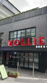 A short, vlog-style video showcasing a visit to Mollie's, an American-style diner in Manchester. The video features shots of the exterior, the interior, the menu, and various dishes including jalapeno cheese croquettes, chicken tenders, a lobster roll, a chicken burger, a cheeseburger, and fries, followed by a group toast with drinks.