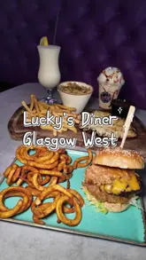 A review of Lucky's Diner in Glasgow, featuring a variety of dishes including a cheesy chicken steak, a burger with curly fries, and decadent desserts like a Matilda cake and brownie. The video includes a brief talking-head segment from the creator and shots of the food and drinks.