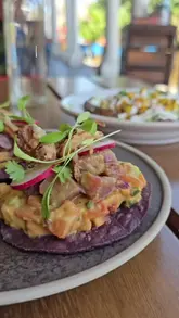 A creator visits Wahaca Brighton to review their summer specials, showcasing the tuna tostada, a customizable sunshine bowl, and a rum-based spritzer cocktail. The video features the creator's personal experience and recommendations, highlighting the fresh, vibrant food and the pleasant outdoor seating area.