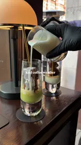 A short, aesthetic clip featuring the preparation of an iced coffee drink, likely involving matcha or pistachio, in a stylish cafe setting.